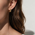 gold flower huggie hoop earrings on model, daisy hoop earrings, floral huggie earrings, small gold flower hoops, textured flower earrings, dainty floral hoops, garden jewelry, nature-inspired earrings, gold huggie earrings, spring floral jewelry, bridesmaid gift, gift for her