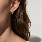 gold flower huggie hoop earrings on model, daisy hoop earrings, floral huggie earrings, small gold flower hoops, textured flower earrings, dainty floral hoops, garden jewelry, nature-inspired earrings, gold huggie earrings, spring floral jewelry, bridesmaid gift, gift for her