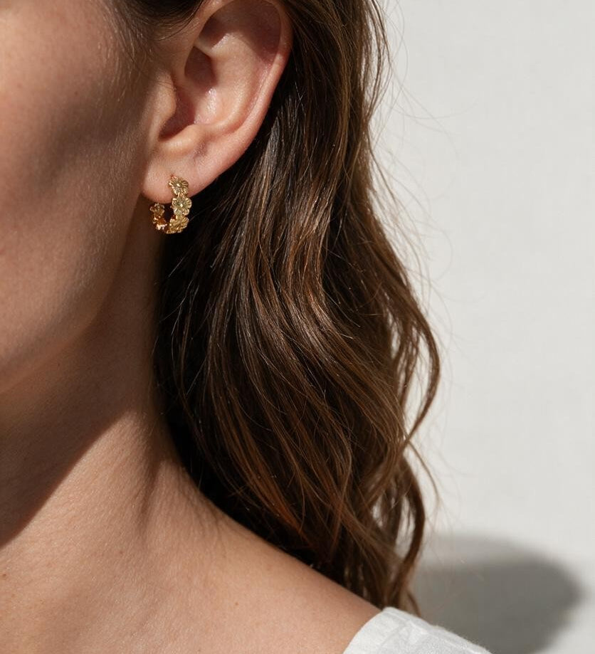 gold flower huggie hoop earrings on model, daisy hoop earrings, floral huggie earrings, small gold flower hoops, textured flower earrings, dainty floral hoops, garden jewelry, nature-inspired earrings, gold huggie earrings, spring floral jewelry, bridesmaid gift, gift for her