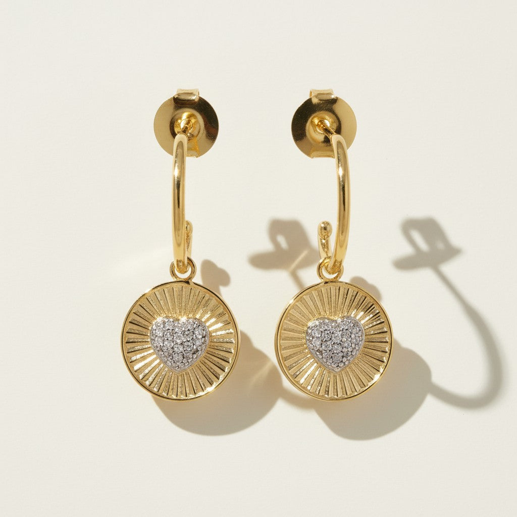 sunburst disc earrings flat lay, gold drop earrings detail, heart pavé earrings pair, huggie hoop drop earrings, textured gold earrings, statement drop earrings, sparkle disc earrings, gold heart earrings