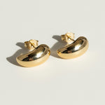 chunky gold dome earrings flat lay, bean shaped gold earrings, sculptural gold stud earrings, high polish gold earrings detail, statement dome earrings, gold earrings push back, modern minimalist gold earrings, glossy gold stud earrings