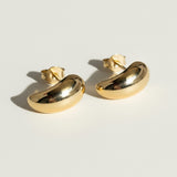 chunky gold dome earrings flat lay, bean shaped gold earrings, sculptural gold stud earrings, high polish gold earrings detail, statement dome earrings, gold earrings push back, modern minimalist gold earrings, glossy gold stud earrings