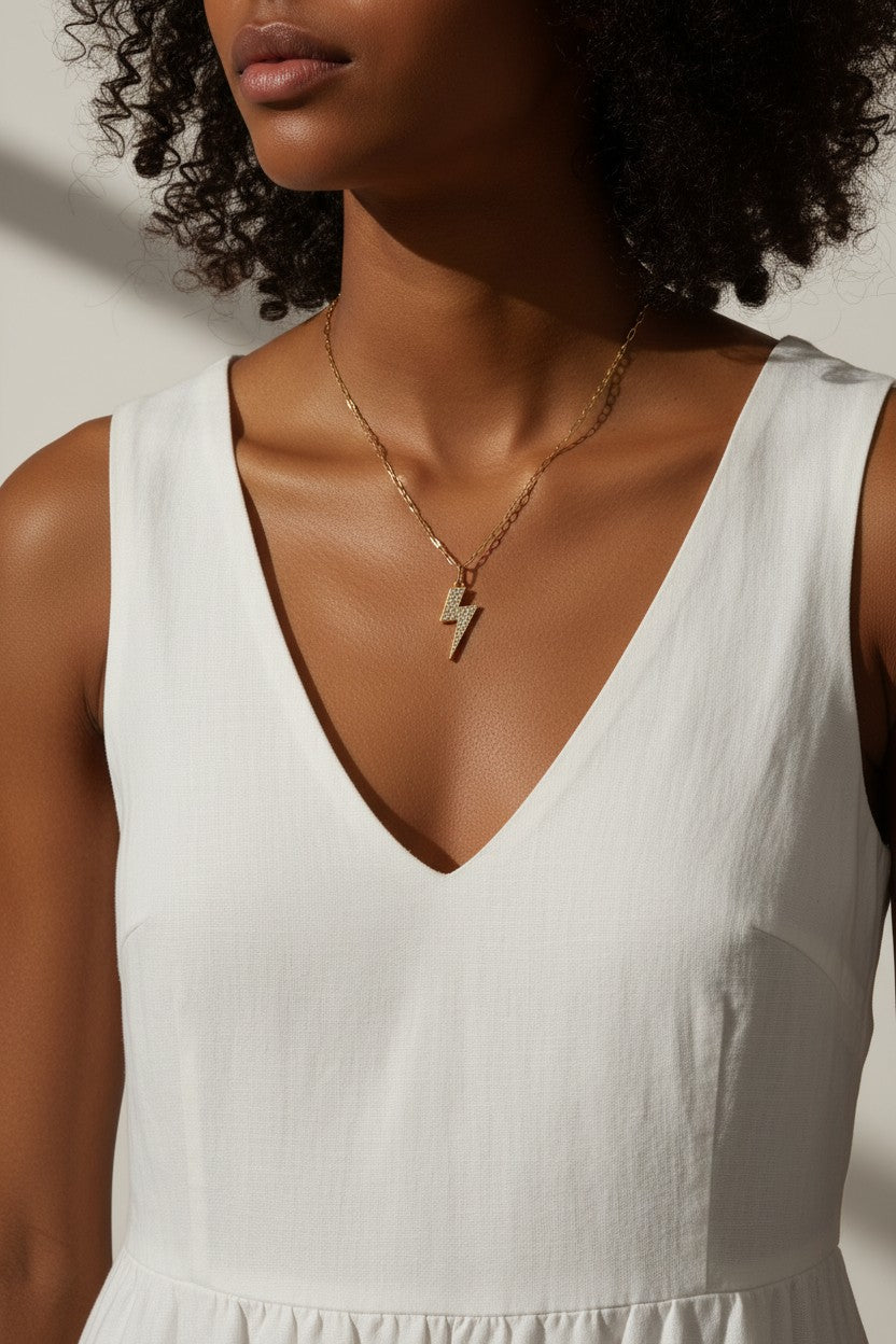 lightning bolt pendant necklace, pave crystal lightning bolt, gold bolt charm necklace, figaro chain necklace, statement pendant detail, crystal encrusted pendant, edgy gold necklace, lightning bolt jewelry