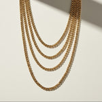 curb chain necklace flat lay, gold curb link necklace detail, classic chain necklace, layered chain necklace, clasp detail necklace, polished chain necklace, gold link necklace, layering necklace set
