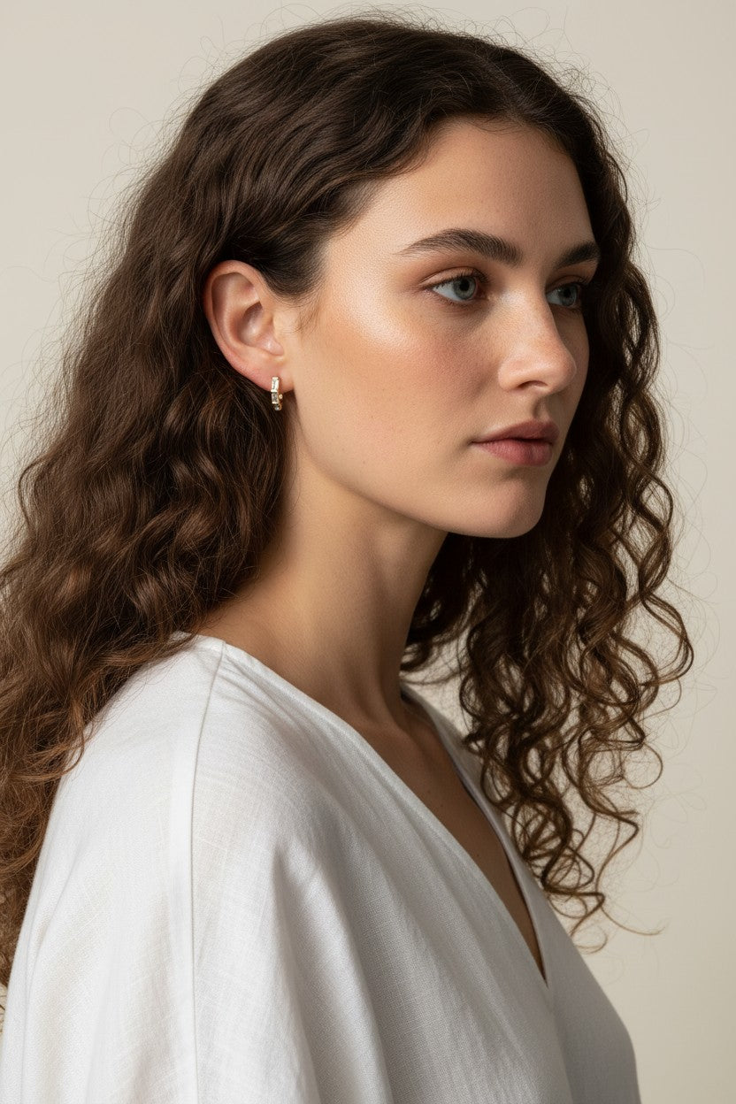 gold baguette hoops on model, huggie hoop earrings worn, emerald huggie hoop earrings, black baguette hoop earrings, clear crystal huggie hoops, gold hoop earrings colorways, baguette stone earrings styled, small gold hoops on ear
