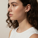 gold baguette hoops on model, huggie hoop earrings worn, emerald huggie hoop earrings, black baguette hoop earrings, clear crystal huggie hoops, gold hoop earrings colorways, baguette stone earrings styled, small gold hoops on ear