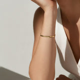 gold herringbone bracelet on wrist, flat gold chain bracelet, slim snake chain bracelet, dainty gold bracelet, minimalist gold bracelet, adjustable gold bracelet, everyday gold bracelet, layering bracelet, shiny gold chain bracelet, women’s gold bracelet, flat herringbone bracelet, sleek wrist jewelry