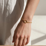 gold rolo chain bracelet on wrist, round clasp bracelet, charm holder bracelet, spring ring clasp bracelet, gold chain bracelet with ring, minimalist gold bracelet, modern gold bracelet, layering bracelet, everyday gold bracelet, interchangeable charm bracelet, circle clasp bracelet, women’s gold bracelet