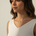 tulip pendant necklace on model, gold flower tag necklace lifestyle, botanical pendant necklace worn, engraved tulip necklace styled, dainty gold necklace on neck, CZ accent pendant, nature-inspired jewelry, rope-edge tag necklace