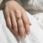 Greek key ring on model, wide gold band ring on hand, meander pattern ring, pavé band ring lifestyle, engraved gold statement ring, geometric gold band styled