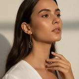 evil eye drop earrings, gold cutout earrings, matte gold dangle earrings, symbolic jewelry, geometric drop earrings, minimalist gold earrings, statement drop earrings, on-model earring photography