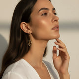 evil eye drop earrings, gold cutout earrings, matte gold dangle earrings, symbolic jewelry, geometric drop earrings, minimalist gold earrings, statement drop earrings, on-model earring photography