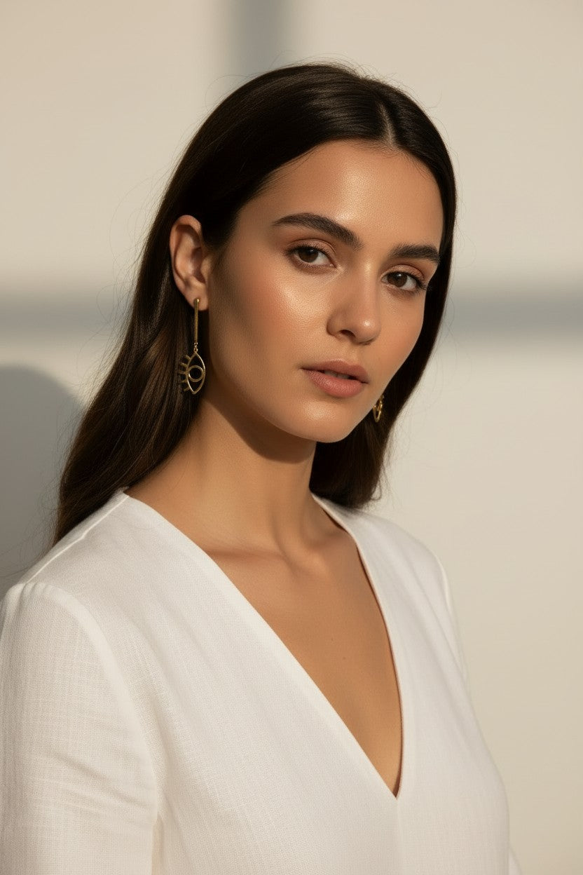 evil eye drop earrings, gold cutout earrings, matte gold dangle earrings, symbolic jewelry, geometric drop earrings, minimalist gold earrings, statement drop earrings, on-model earring photography