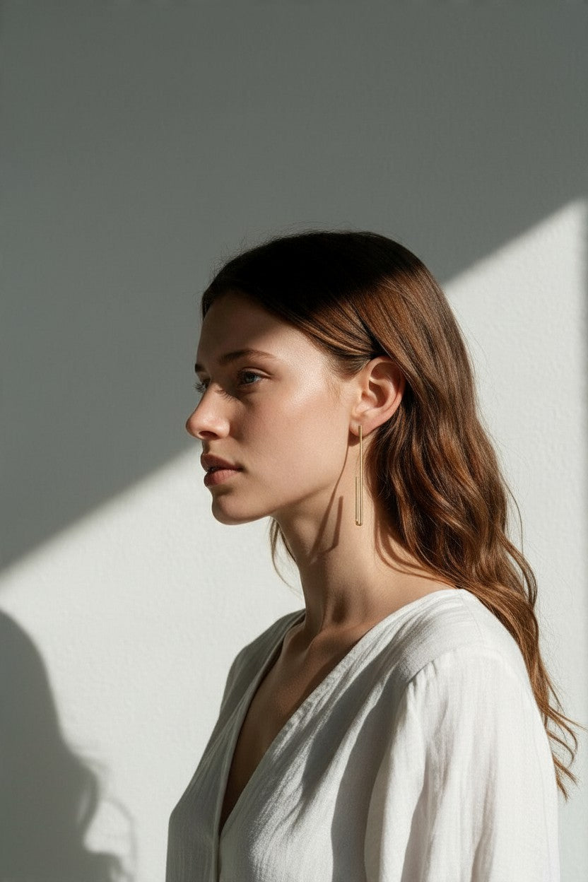 long gold rectangle earrings on model, geometric wire earrings, minimalist gold drop earrings, elongated open hoop earrings, modern gold earrings, lightweight statement earrings, architectural earrings, thin gold wire earrings, contemporary gold jewelry, linear gold earrings, women’s geometric earrings, elegant everyday earrings