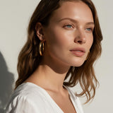 classic gold hoop earrings on model, gold tube hoop earrings, polished gold hoops, medium gold hoop earrings, thick gold hoops, everyday gold hoops, timeless hoop earrings, minimalist gold hoops, lightweight chunky hoops, hoop earrings for long hair, gift for her, summer linen style jewelry