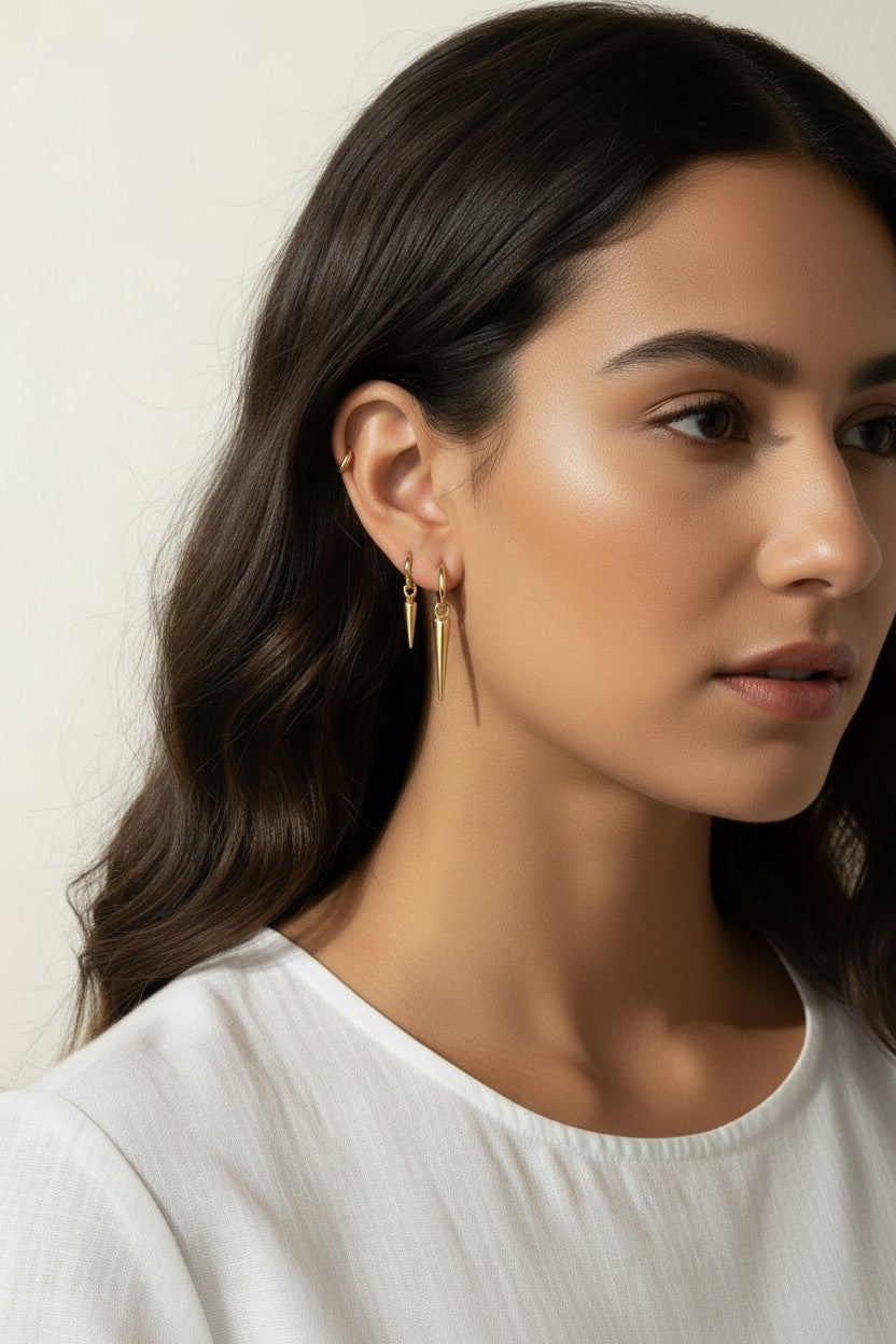 gold spike charm earrings worn, hoop earrings with charm styled, layered ear stack gold, triangle charm hoop fit, minimalist edgy earring lifestyle photo, gold ear cuff and hoop pairing