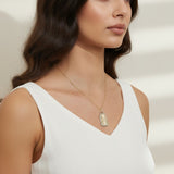 love pendant necklace on model, gold tag necklace lifestyle, sunburst pendant necklace worn, pavé love necklace styled, engraved love pendant on neck, long chain pendant necklace, statement gold necklace, script love necklace outfit