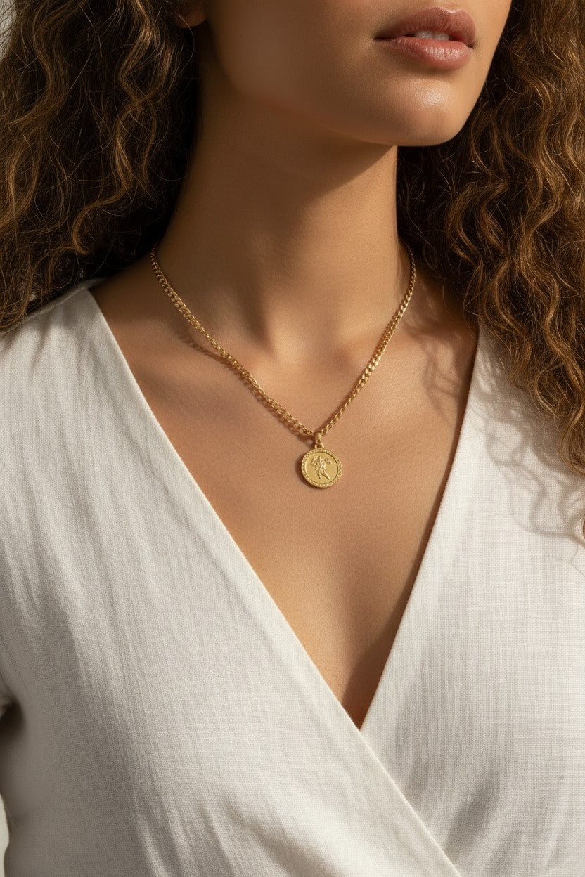This series of close-up portraits shows a gold curb chain necklace featuring a round coin pendant engraved with a classical winged figure, worn at the collarbone for a layered, vintage-inspired look. Captured on two different models from front-facing and side-profile angles, the pendant's textured beaded border and detailed relief engraving are shown at true scale, giving shoppers a clear sense of the coin's dimension and how the substantial curb chain sits against the neckline