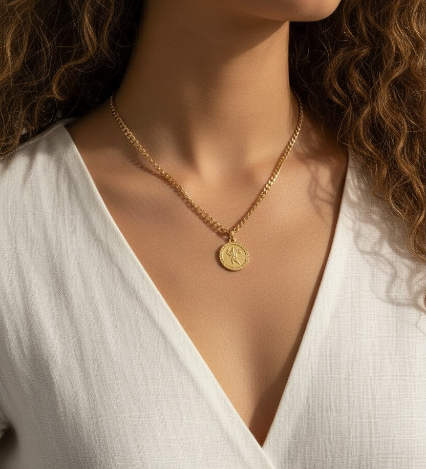This series of close-up portraits shows a gold curb chain necklace featuring a round coin pendant engraved with a classical winged figure, worn at the collarbone for a layered, vintage-inspired look. Captured on two different models from front-facing and side-profile angles, the pendant's textured beaded border and detailed relief engraving are shown at true scale, giving shoppers a clear sense of the coin's dimension and how the substantial curb chain sits against the neckline