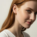 square huggie hoop earrings on model, gold geometric earrings worn, modern hoop earrings lifestyle, angular gold hoops styled, polished square earrings, minimalist huggie earrings, statement gold hoops, architectural earrings on ear