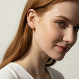 square huggie hoop earrings on model, gold geometric earrings worn, modern hoop earrings lifestyle, angular gold hoops styled, polished square earrings, minimalist huggie earrings, statement gold hoops, architectural earrings on ear