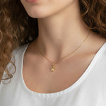 gold crown pendant resting at the collarbone on a fine box chain, styled with a simple white scoop-neck top for a clean, elevated look. Captured from front-facing and close-up angles, the open crown silhouette and its cubic zirconia-tipped points are shown at true scale against soft, warm-toned skin, giving shoppers a clear sense of the pendant's petite, delicate proportions and dainty drop length Crown Pendant Necklace Worn On-Model