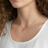 gold crown pendant resting at the collarbone on a fine box chain, styled with a simple white scoop-neck top for a clean, elevated look. Captured from front-facing and close-up angles, the open crown silhouette and its cubic zirconia-tipped points are shown at true scale against soft, warm-toned skin, giving shoppers a clear sense of the pendant's petite, delicate proportions and dainty drop length Crown Pendant Necklace Worn On-Model