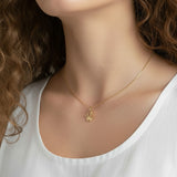 gold crown pendant resting at the collarbone on a fine box chain, styled with a simple white scoop-neck top for a clean, elevated look. Captured from front-facing and close-up angles, the open crown silhouette and its cubic zirconia-tipped points are shown at true scale against soft, warm-toned skin, giving shoppers a clear sense of the pendant's petite, delicate proportions and dainty drop length Crown Pendant Necklace Worn On-Model