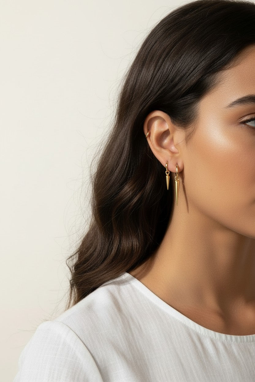 gold spike charm earrings worn, hoop earrings with charm styled, layered ear stack gold, triangle charm hoop fit, minimalist edgy earring lifestyle photo, gold ear cuff and hoop pairing