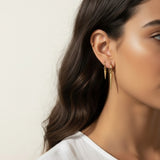 gold spike charm earrings worn, hoop earrings with charm styled, layered ear stack gold, triangle charm hoop fit, minimalist edgy earring lifestyle photo, gold ear cuff and hoop pairing