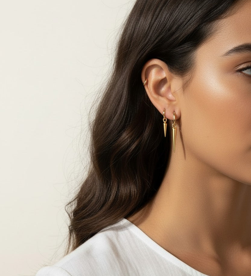 gold spike charm earrings worn, hoop earrings with charm styled, layered ear stack gold, triangle charm hoop fit, minimalist edgy earring lifestyle photo, gold ear cuff and hoop pairing