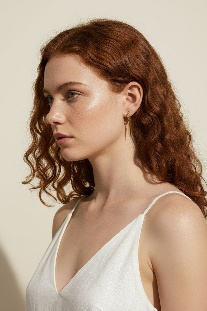 emerald huggie hoop earrings, gold huggie hoops with charm, emerald pavé spike earrings, huggie hoop on model, green crystal spike drop earrings, gold and emerald jewelry, everyday huggie hoops, pavé spike huggie hoop
