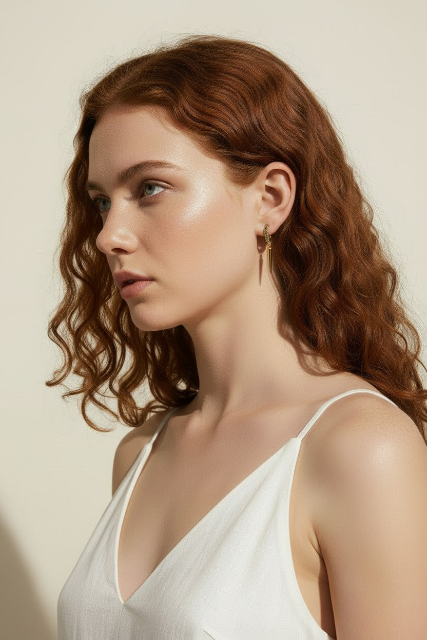 emerald huggie hoop earrings, gold huggie hoops with charm, emerald pavé spike earrings, huggie hoop on model, green crystal spike drop earrings, gold and emerald jewelry, everyday huggie hoops, pavé spike huggie hoop