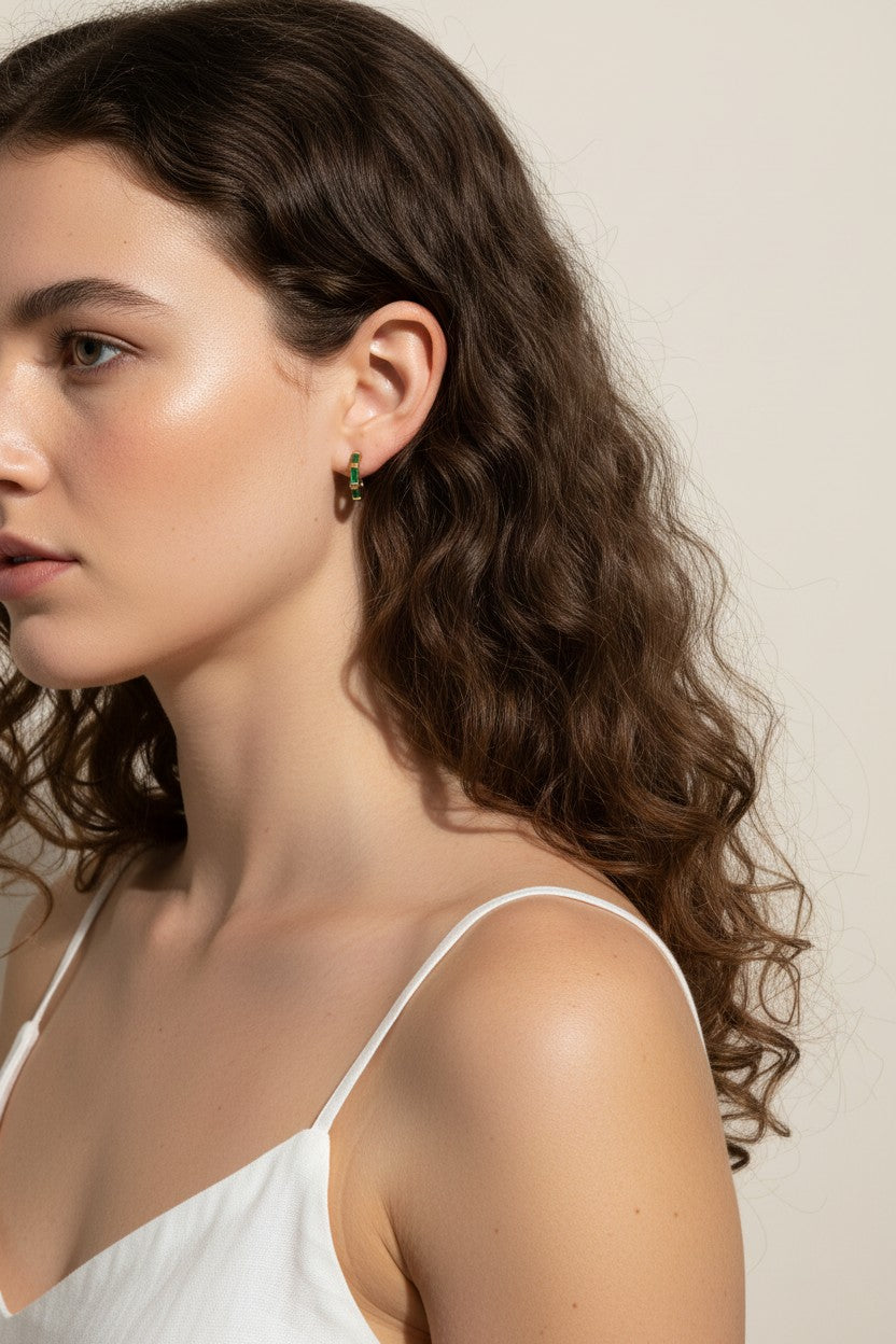 gold baguette hoops on model, huggie hoop earrings worn, emerald huggie hoop earrings, black baguette hoop earrings, clear crystal huggie hoops, gold hoop earrings colorways, baguette stone earrings styled, small gold hoops on ear