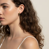 gold baguette hoops on model, huggie hoop earrings worn, emerald huggie hoop earrings, black baguette hoop earrings, clear crystal huggie hoops, gold hoop earrings colorways, baguette stone earrings styled, small gold hoops on ear