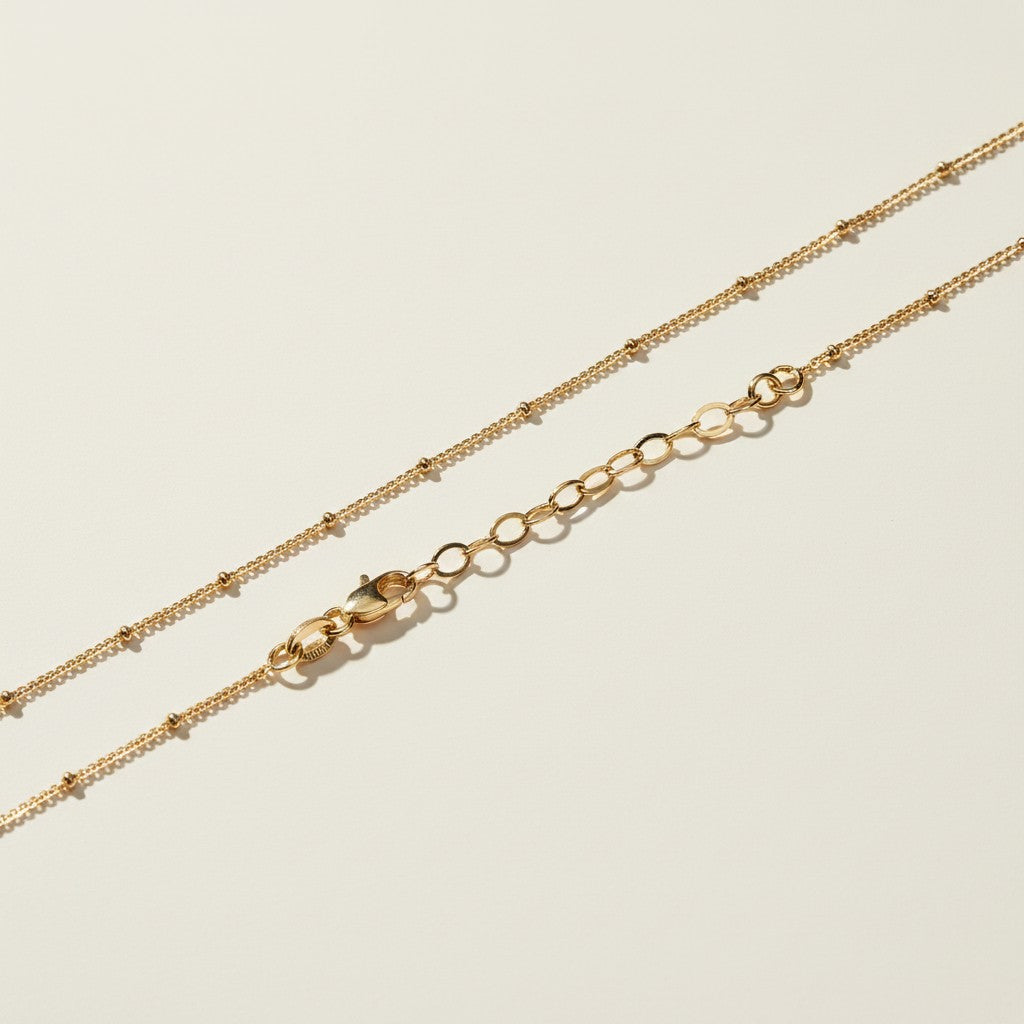layered satellite necklace flat lay, three strand necklace clasp, cascading gold necklace construction, beaded chain necklace detail, 18k gold satellite chain, graduated necklace flat lay, multi strand necklace clasp detail, delicate layered gold necklace