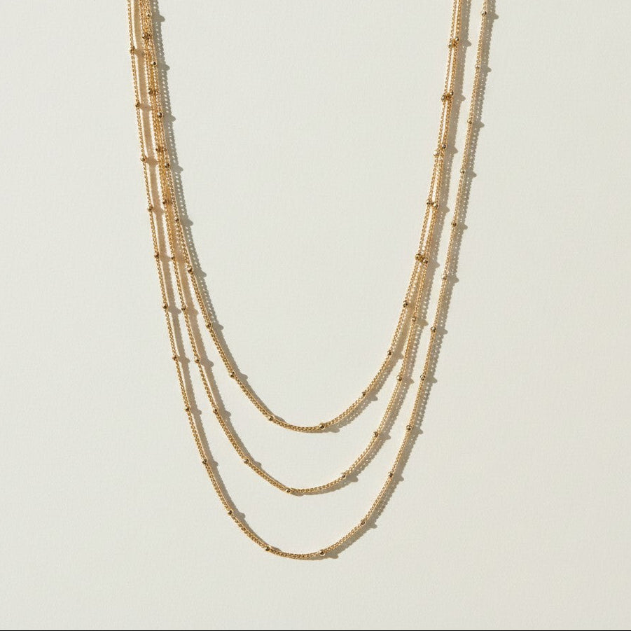 layered satellite necklace flat lay, three strand necklace clasp, cascading gold necklace construction, beaded chain necklace detail, 18k gold satellite chain, graduated necklace flat lay, multi strand necklace clasp detail, delicate layered gold necklace