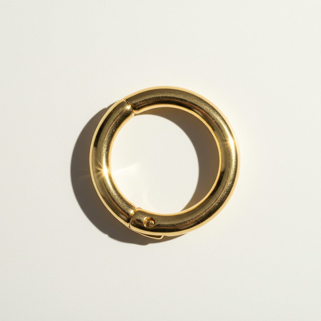 This gold seamless hoop earring features a smooth, rounded tube design with a nearly invisible hinge mechanism, creating a clean, uninterrupted circular silhouette. The hinged closure clicks securely open and shut, offering a comfortable, everyday-wearable fit without a visible clasp or post. 