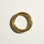 This gold seamless hoop earring features a smooth, rounded tube design with a nearly invisible hinge mechanism, creating a clean, uninterrupted circular silhouette. The hinged closure clicks securely open and shut, offering a comfortable, everyday-wearable fit without a visible clasp or post. 