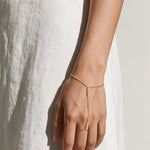 gold hand chain bracelet on model, slave bracelet, finger ring bracelet, hand harness jewelry, crystal hand chain, bridal hand chain, bracelet with ring attached, dainty gold hand chain, delicate hand jewelry, party hand jewelry, wedding hand chain, women’s hand chain