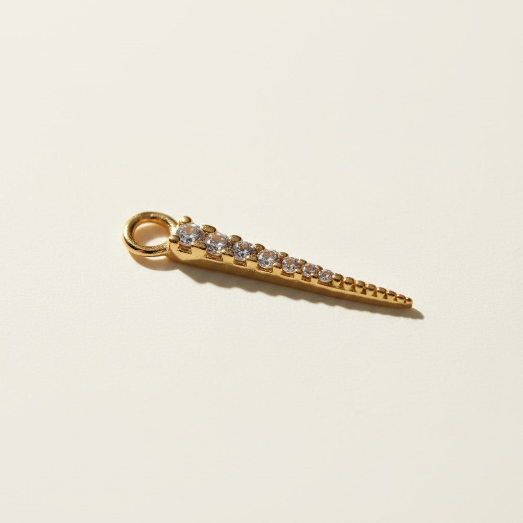 bold CZ spear earring charm — a tapered gold spike lined with a graduated row of sparkling cubic zirconia stones that narrows to a fine, polished point. Crafted in 18k gold overlay, this 20mm charm is designed to attach easily via its jump ring to our 9mm or 11mm seamless hoops (sold separately), letting you customize your hoops with a touch of shimmer and edge.