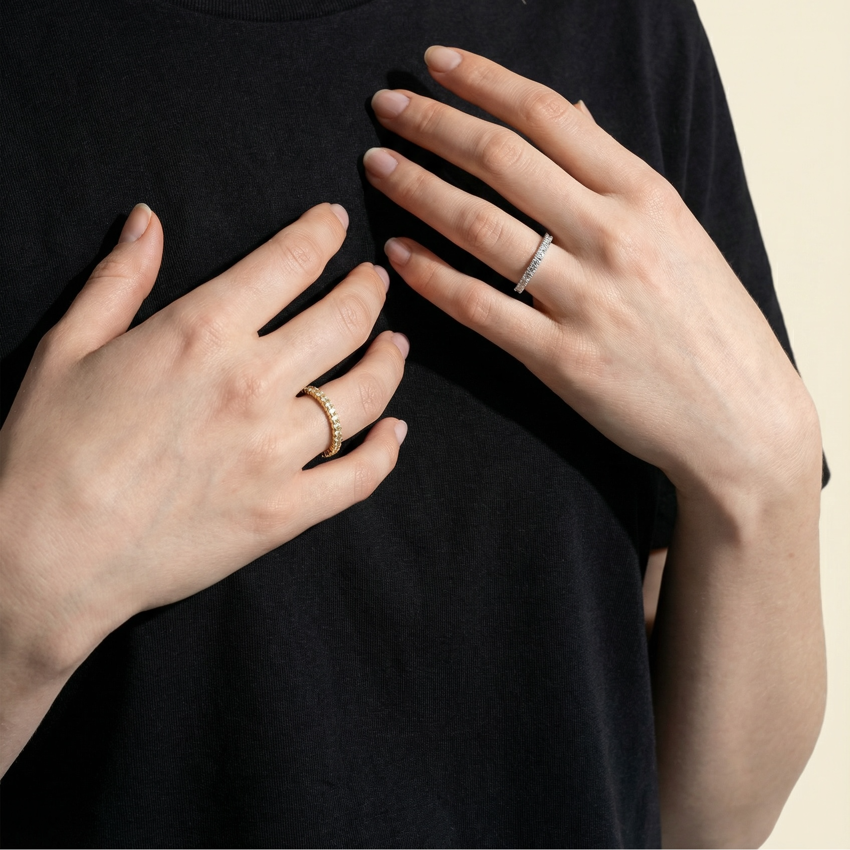 Person wearing a black t-shirt with visible jewelry on a beige background