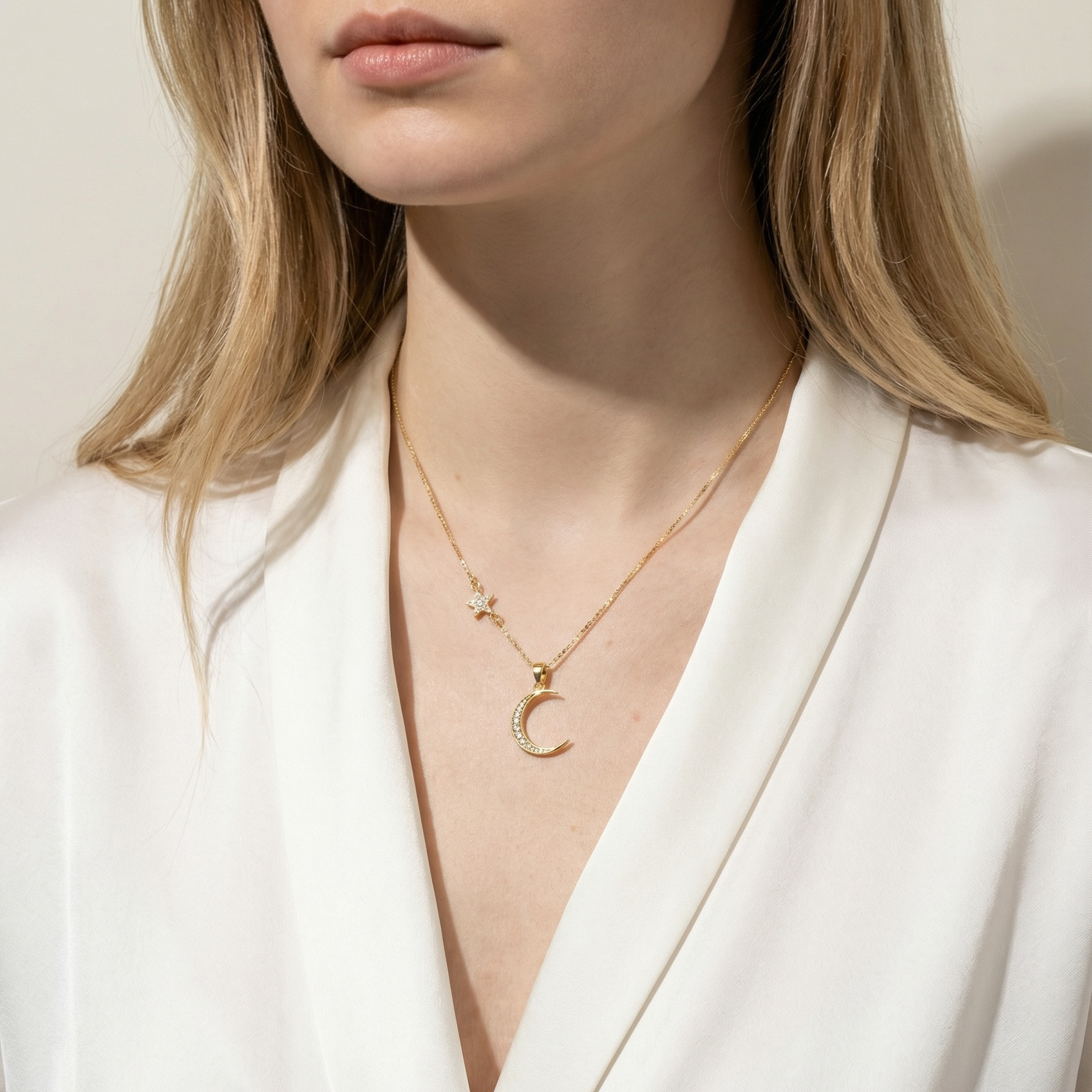 Woman wearing a gold necklace with a Crescent moon pendant against a neutral background