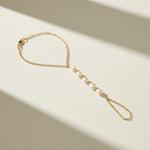 pearl hand chain flat lay, pearl bracelet ring chain, gold hand chain jewelry, pearl slave bracelet detail, hand chain construction, bridal hand jewelry flat lay, delicate pearl hand chain, wrist to finger chain bracelet