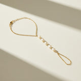 pearl hand chain flat lay, pearl bracelet ring chain, gold hand chain jewelry, pearl slave bracelet detail, hand chain construction, bridal hand jewelry flat lay, delicate pearl hand chain, wrist to finger chain bracelet