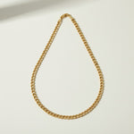 curb chain necklace flat lay, gold curb link necklace detail, classic chain necklace, layered chain necklace, clasp detail necklace, polished chain necklace, gold link necklace, layering necklace set