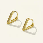 A pair of gold geometric huggie hoop earrings with small clear stones set along the front edge, displayed on a warm off-white background with soft shadows.