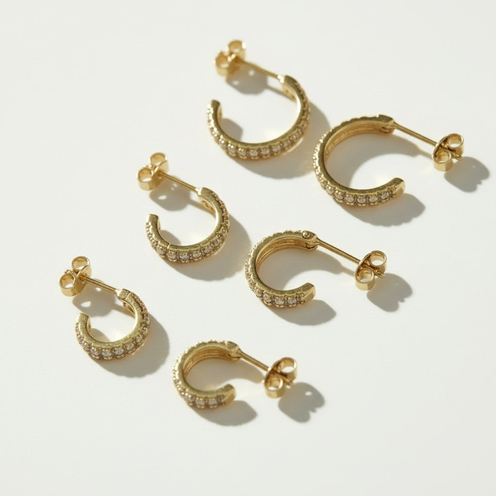 pavé huggie hoop earrings, gold huggie earrings flat lay, small pavé hoop earrings, sparkle hoop earrings detail, hinged huggie hoops, everyday gold hoops, ear stack earrings, minimalist gold hoops