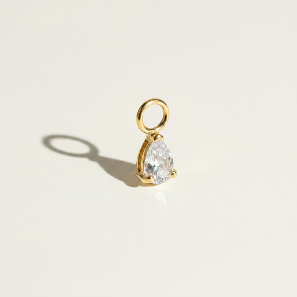 These interchangeable earring charms feature a pear-cut crystal set in a four-prong gold setting, topped with a round jump ring for easy attachment to hoops or huggies. Available in two colorways — a vivid emerald green and a sparkling clear crystal — the charms let shoppers customize and mix up their earring stack with a single pair of base hoops. 
