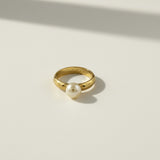 This 18k gold filled ring features a smooth, rounded domed band paired with a single freshwater pearl seated flush against one edge, creating a modern take on a classic solitaire silhouette. The pearl's soft luster contrasts beautifully with the ring's high-polish gold finish, while the substantial, rounded band offers a comfortable, everyday-wearable fit